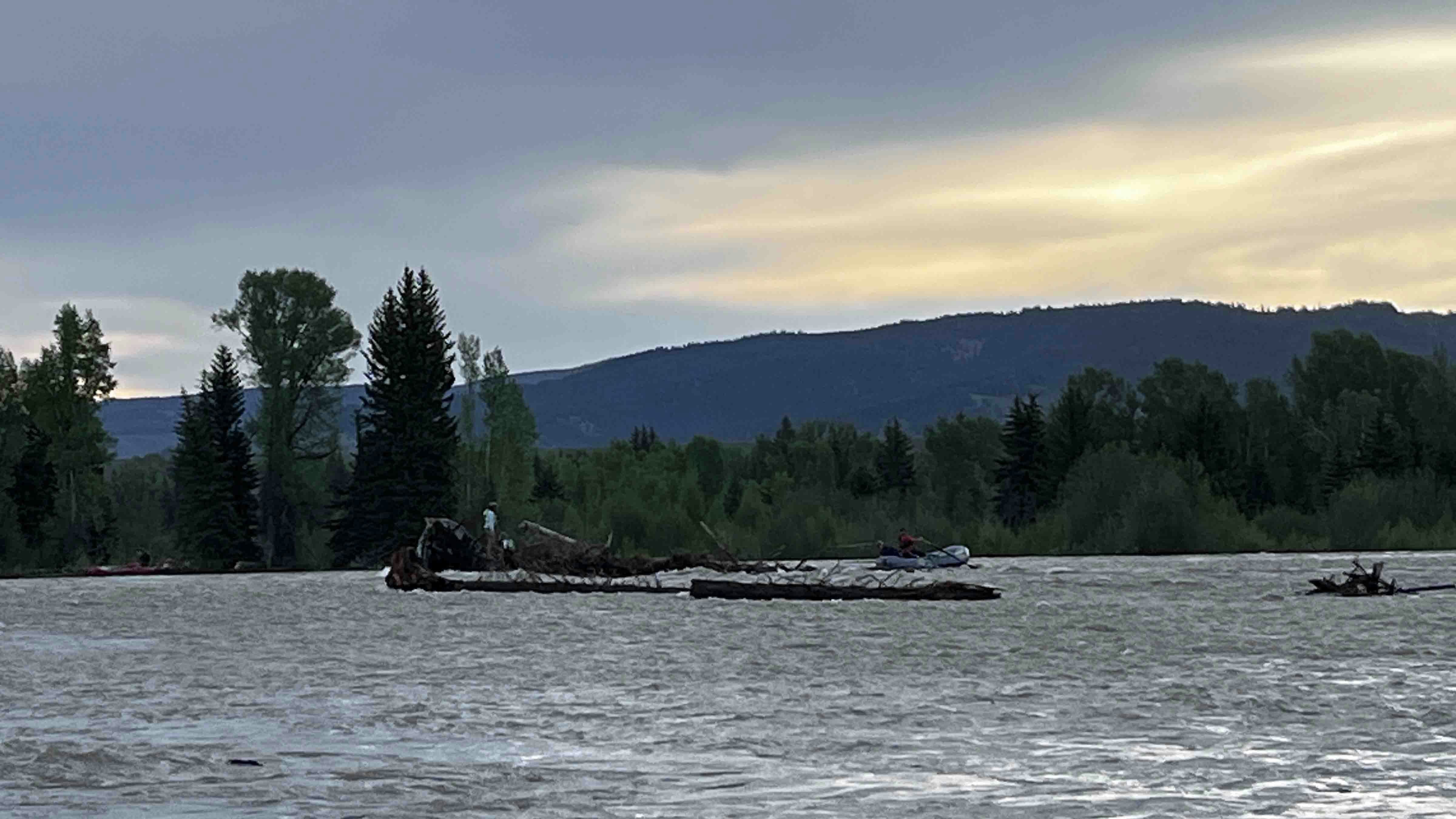 Rescuers try to reach stranded rafters, after their raft hit a snag and flipped in the Snake River in Grand Teton National Park late Saturday.