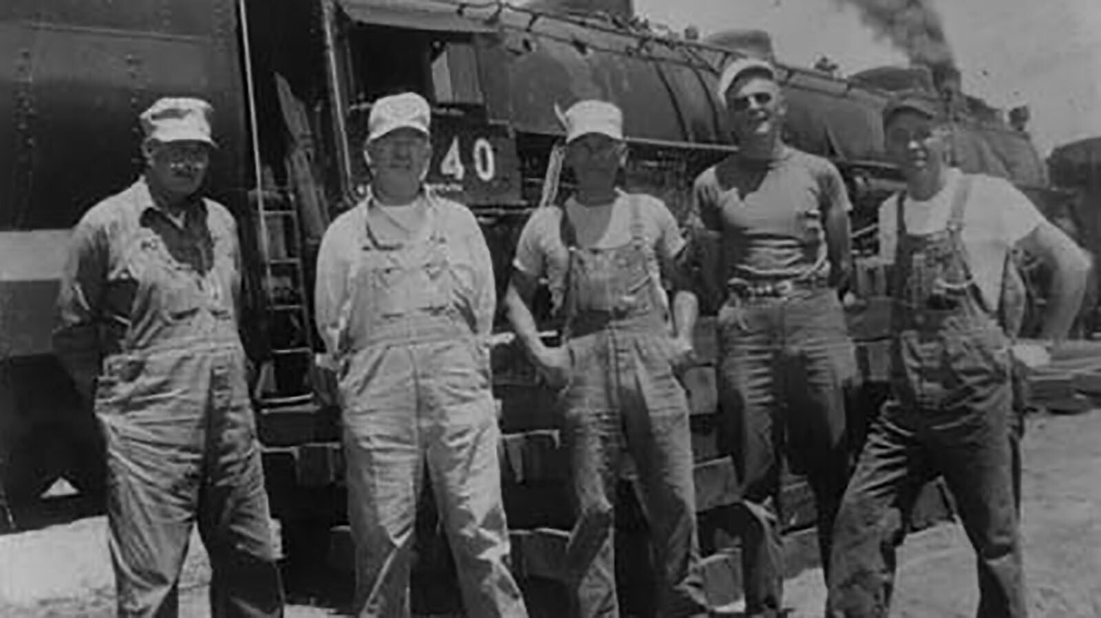 A train crew from the steam era pose outside their train.