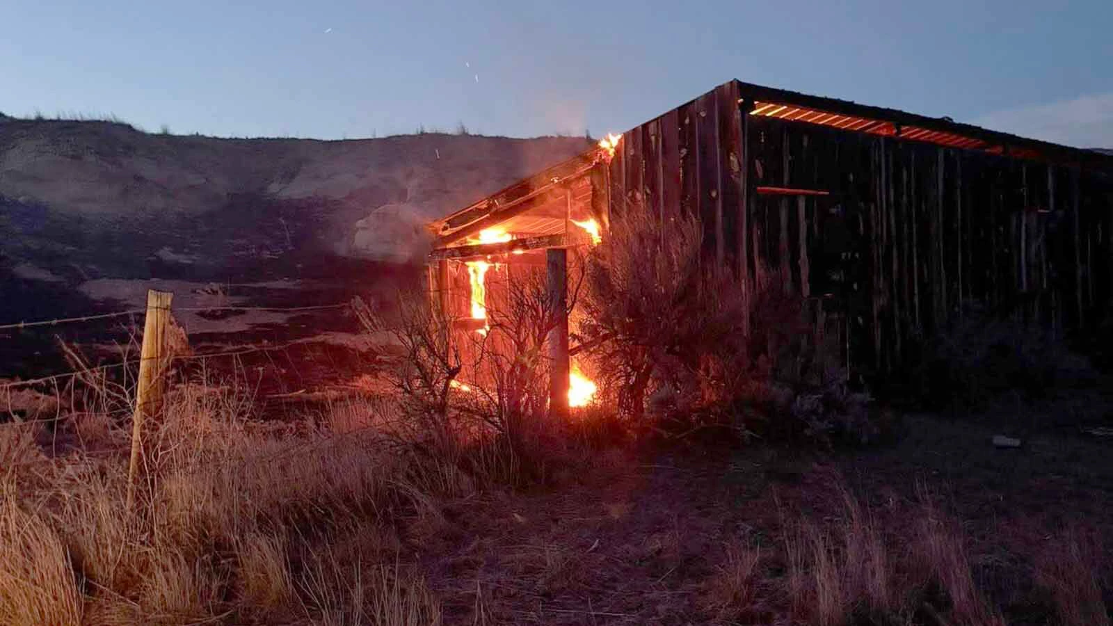 Firefighters work a glowing fireline at dusk during the Raven Creek Fire, one of two wildfires to strike the same corner of Weston County in less than a week.