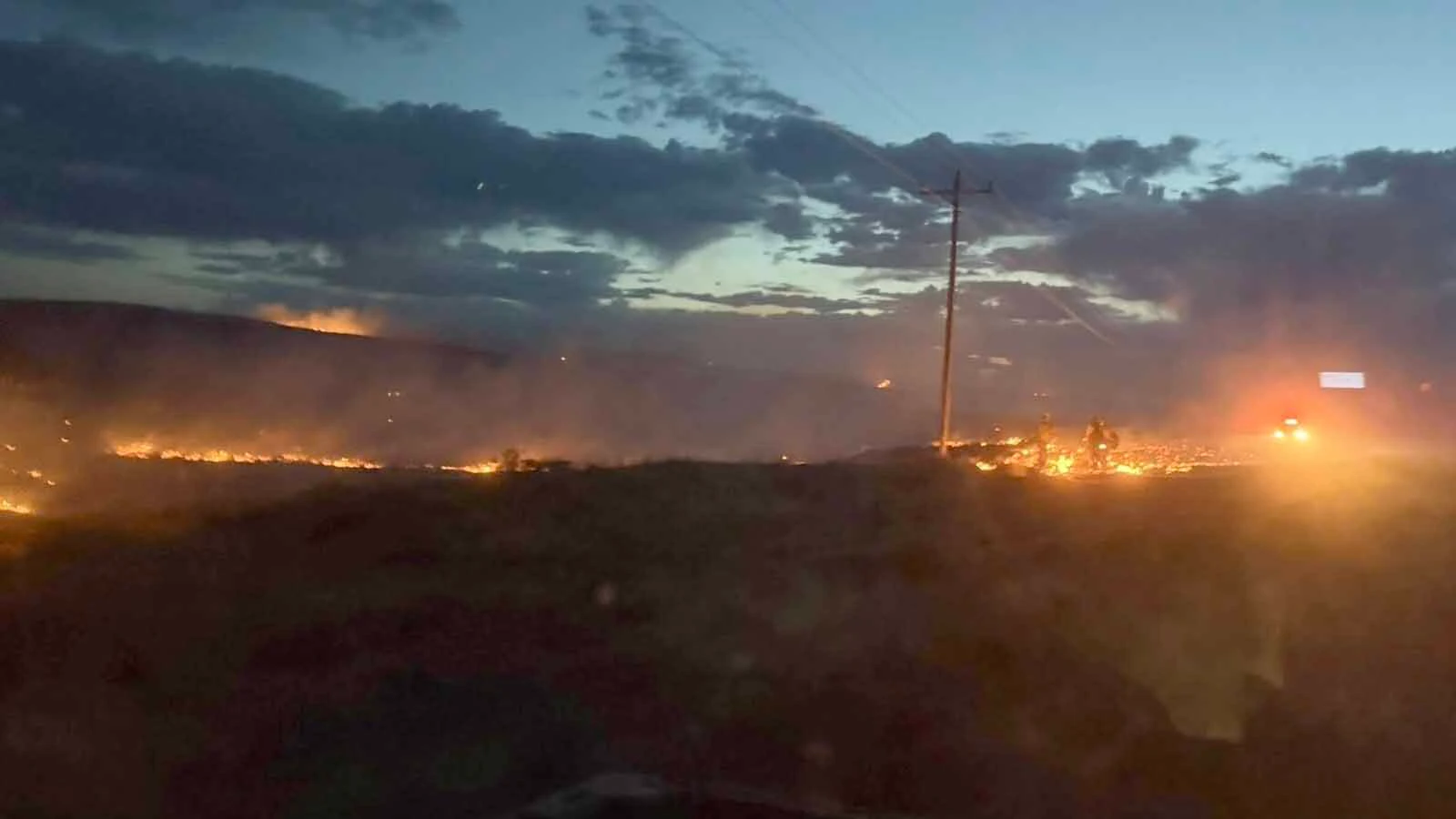 Firefighters work a glowing fireline at dusk during the Raven Creek Fire, one of two wildfires to strike the same corner of Weston County in less than a week.