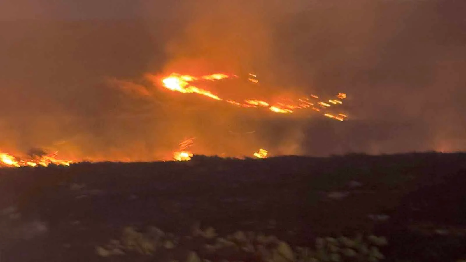 Firefighters work a glowing fireline at dusk during the Raven Creek Fire, one of two wildfires to strike the same corner of Weston County in less than a week.