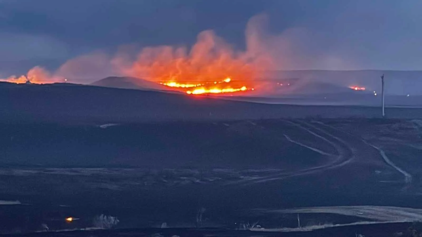 Firefighters work a glowing fireline at dusk during the Raven Creek Fire, one of two wildfires to strike the same corner of Weston County in less than a week.