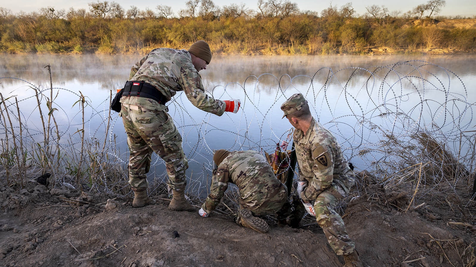 Texas National Guard members repair razor wire at the U.S. border after a surge of immigrants damaged it.