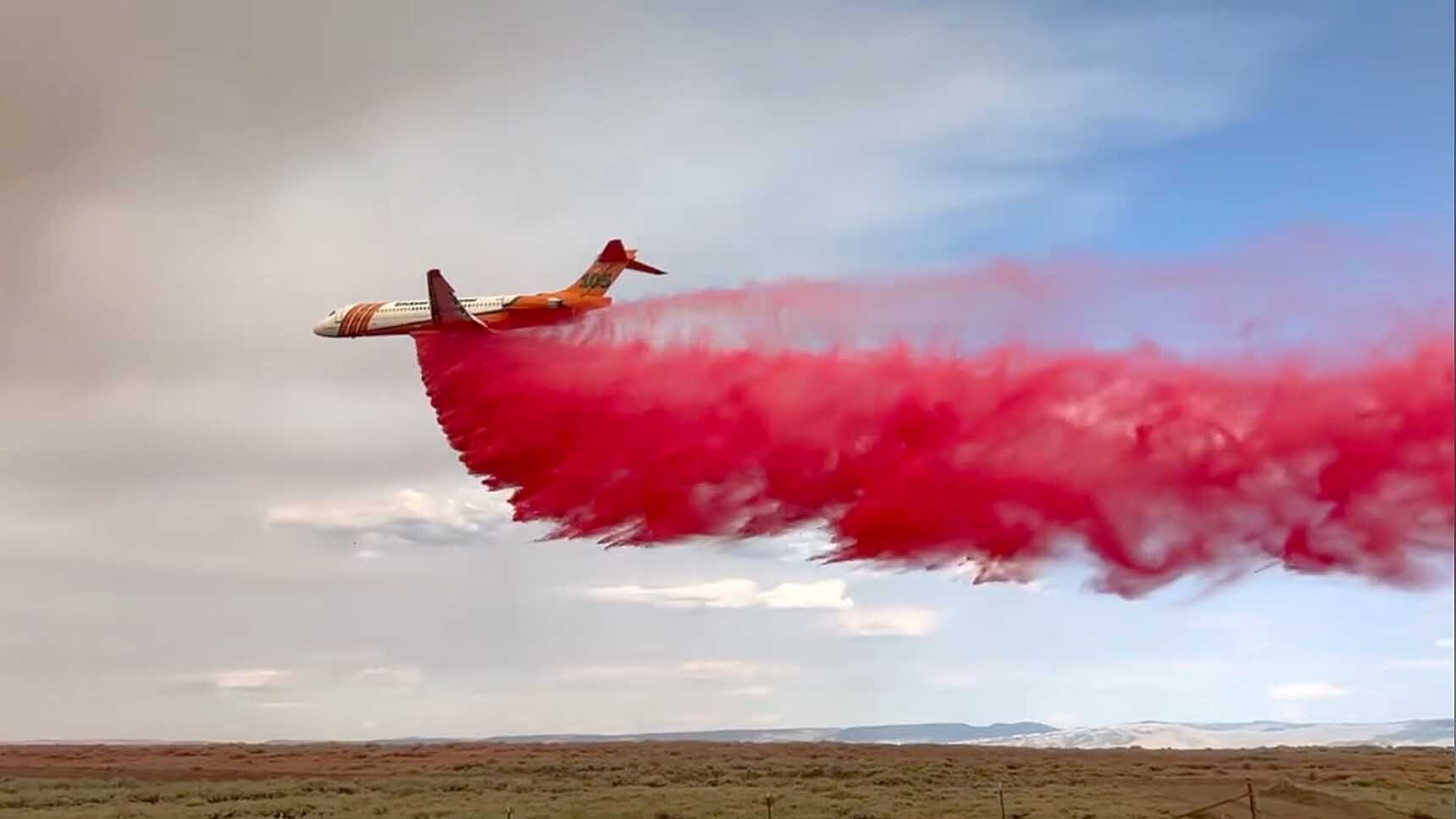 A large tanker jet drops fire-retardant slurry around the perimeter of the Red Canyon Fire.