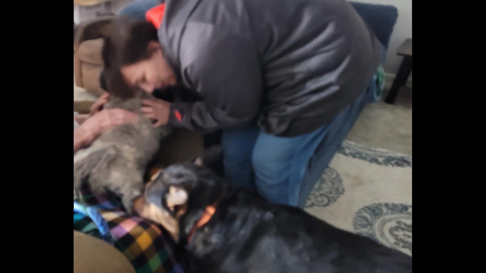 Homeowner Karo Hamilton nuzzles Willie, who was found in the rubble of a Sheridan house that became the scene of a standoff Tuesday. Mia, another dog rescued from the home, joins in the hug.