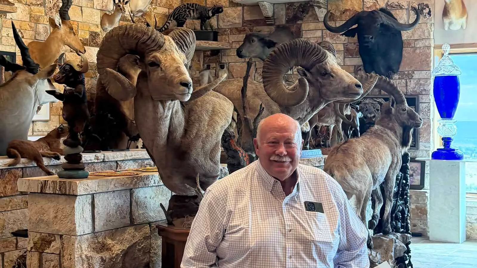 Rick Bonander sits among dozens of trophies collected during a lifetime of hunting and adventure.