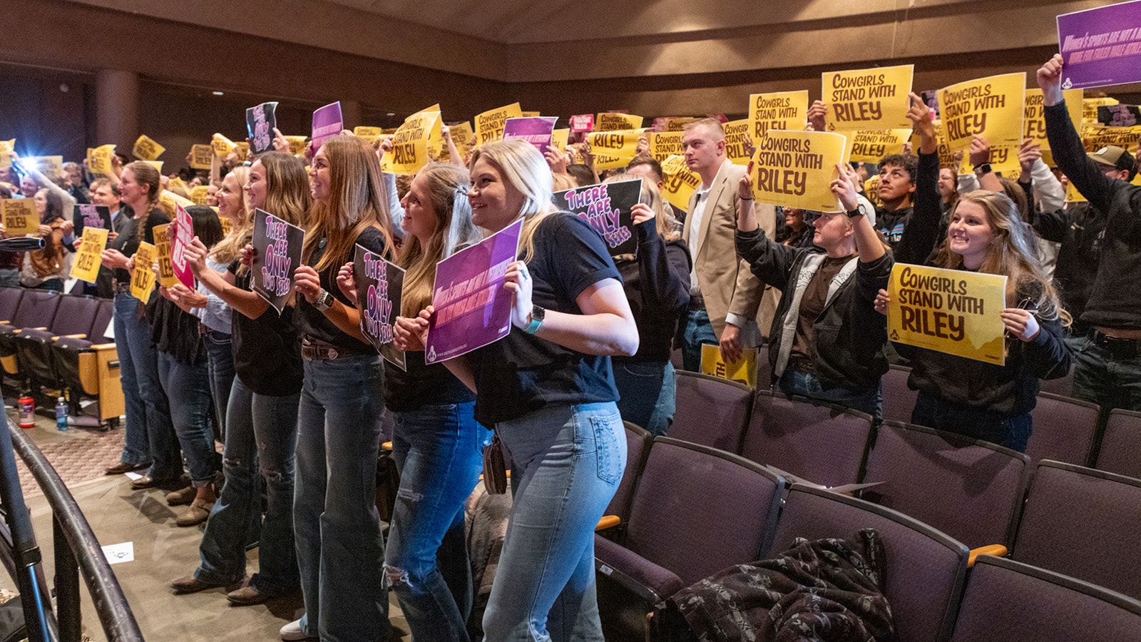A group of supporters cheer and hold up "Cowgirls Stand With Riley" signs duringTuesday as Riley Gaines speaks at the University of Wyoming in Laramie.