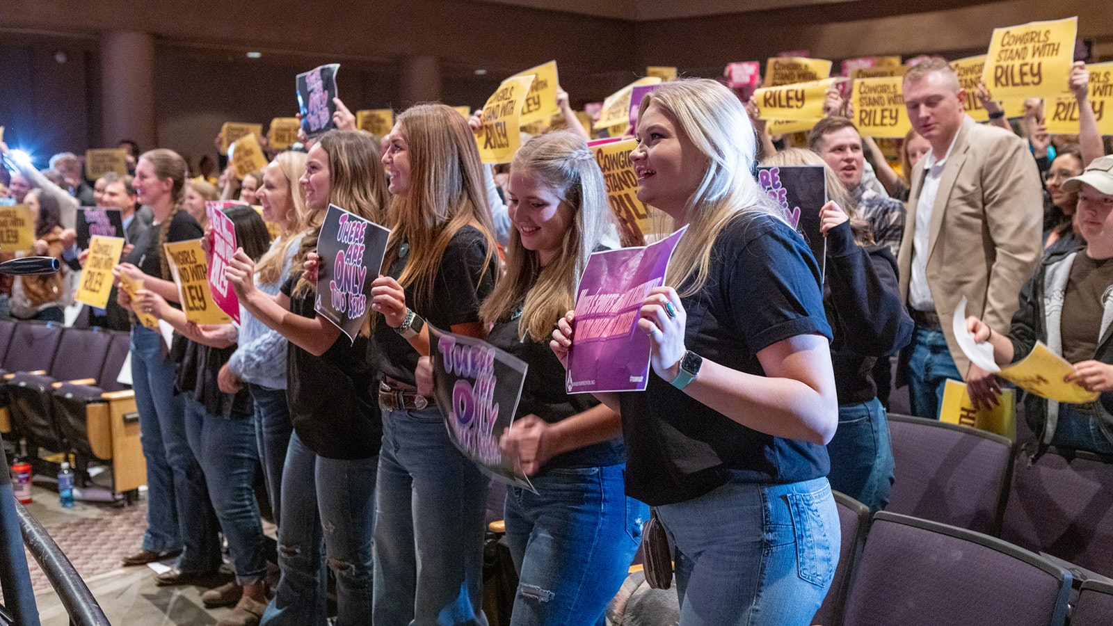 A large section of the crowd holds up "Cowgirls Stand With Riley" signs during Tuesdays event at the University of Wyoming in Laramie.