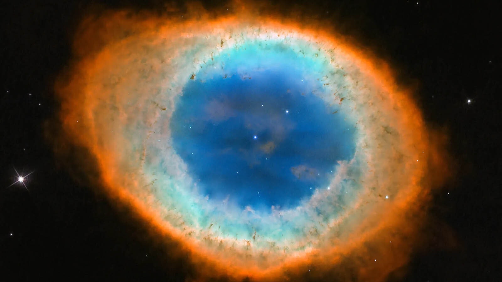 M57, or the Ring Nebula, is a planetary nebula, the glowing remains of a sun-like star. The tiny white dot in the center of the nebula is the star’s hot core, called a white dwarf.