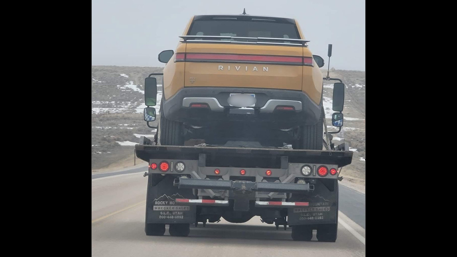 A tow truck takes a Rivian that was stranded while traveling between Riverton and Rock Springs on Friday.