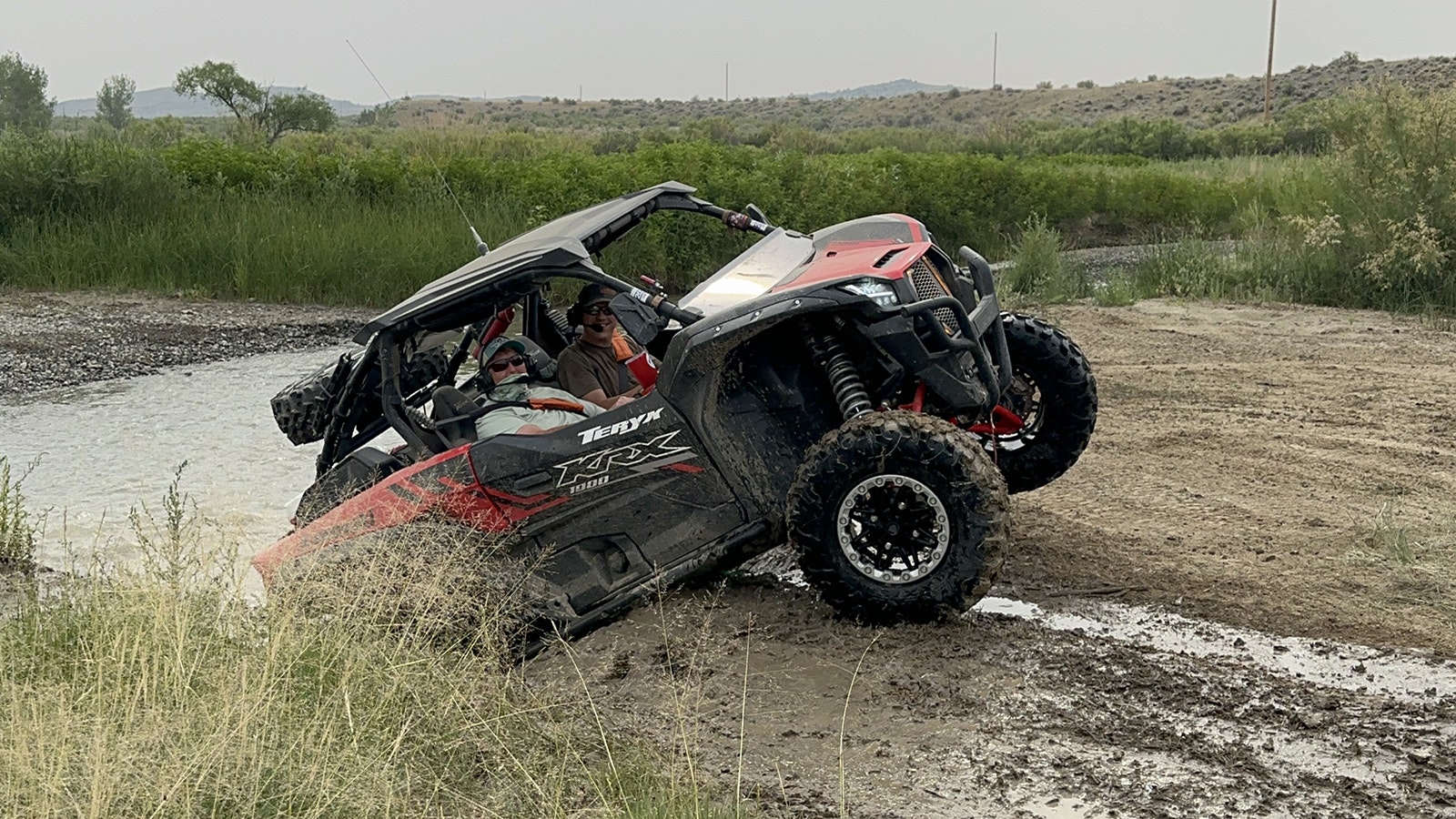 A side-by-side crawls out of the Cotton Creek on three wheels in Wagonhound Off-Road Park