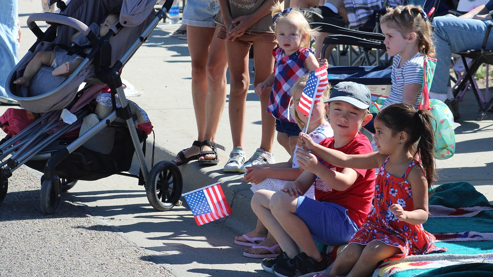 Olivia Suarez, 4, right, takes an American flag from Easton Harris, 8, while watching the Rock Springs Liberty Parade on July 4, 2024.