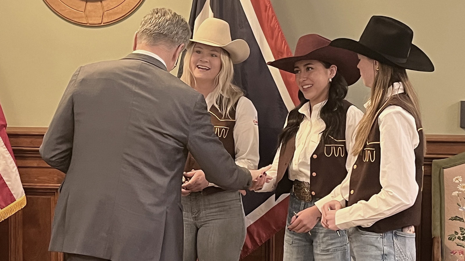 Gov. Mark Gordon greets members of the University of Wyoming rodeo team at Friday's bill signing approving a rodeo-themed license plate.