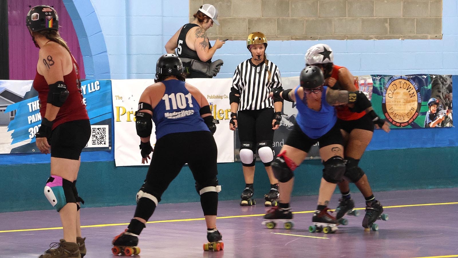 A skater at right, puts a block on the opposing team’s jammer, designated with the star on her helmet.