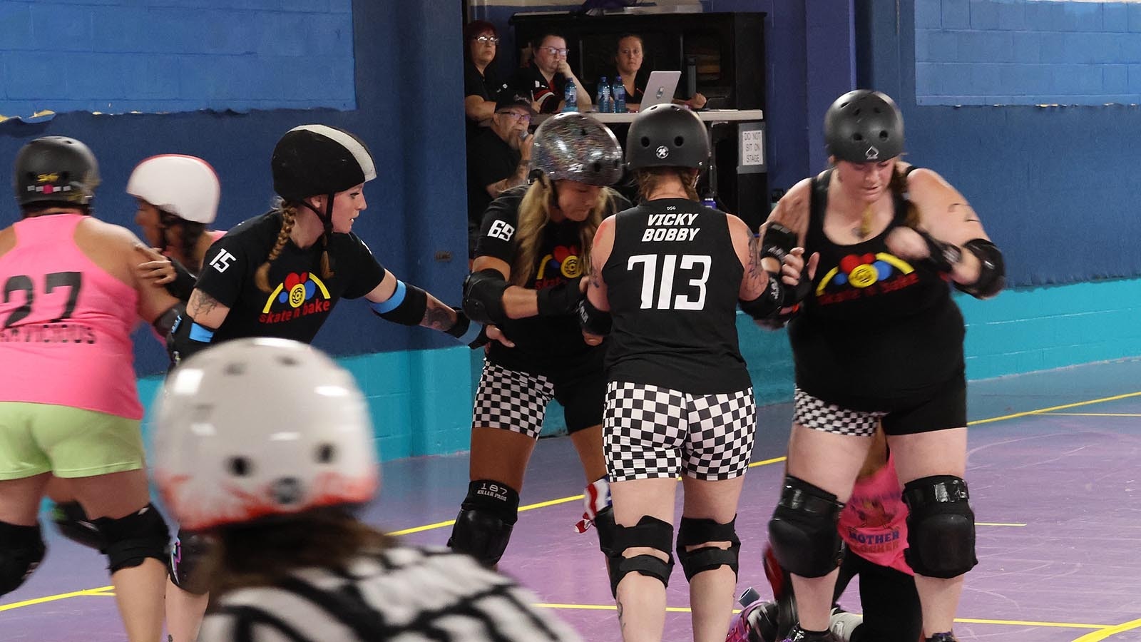 Members of the Skate n Bake team try to keep the jammer from the opposing team, kneeling at right, from scoring points.