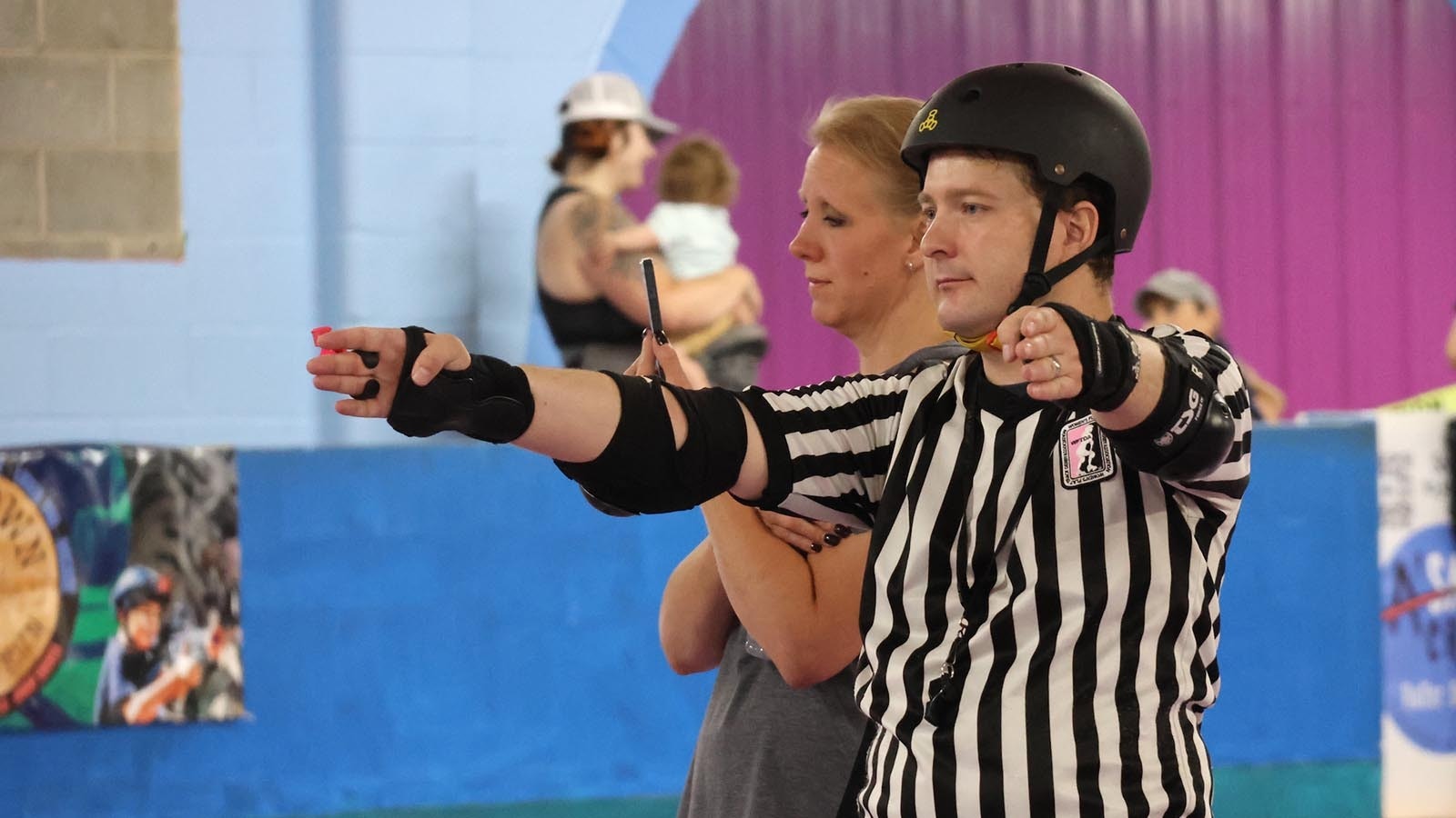 A referee follows the jam on the rink. Referees follow matches closely and  call penalties which can send a player to the penalty box.