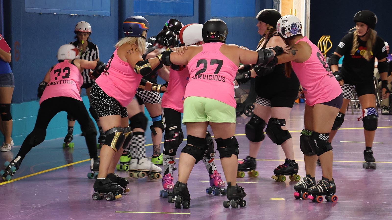 Both teams form a jam to keep the jammers at left and far right, designated by stars on helmet, from getting through.