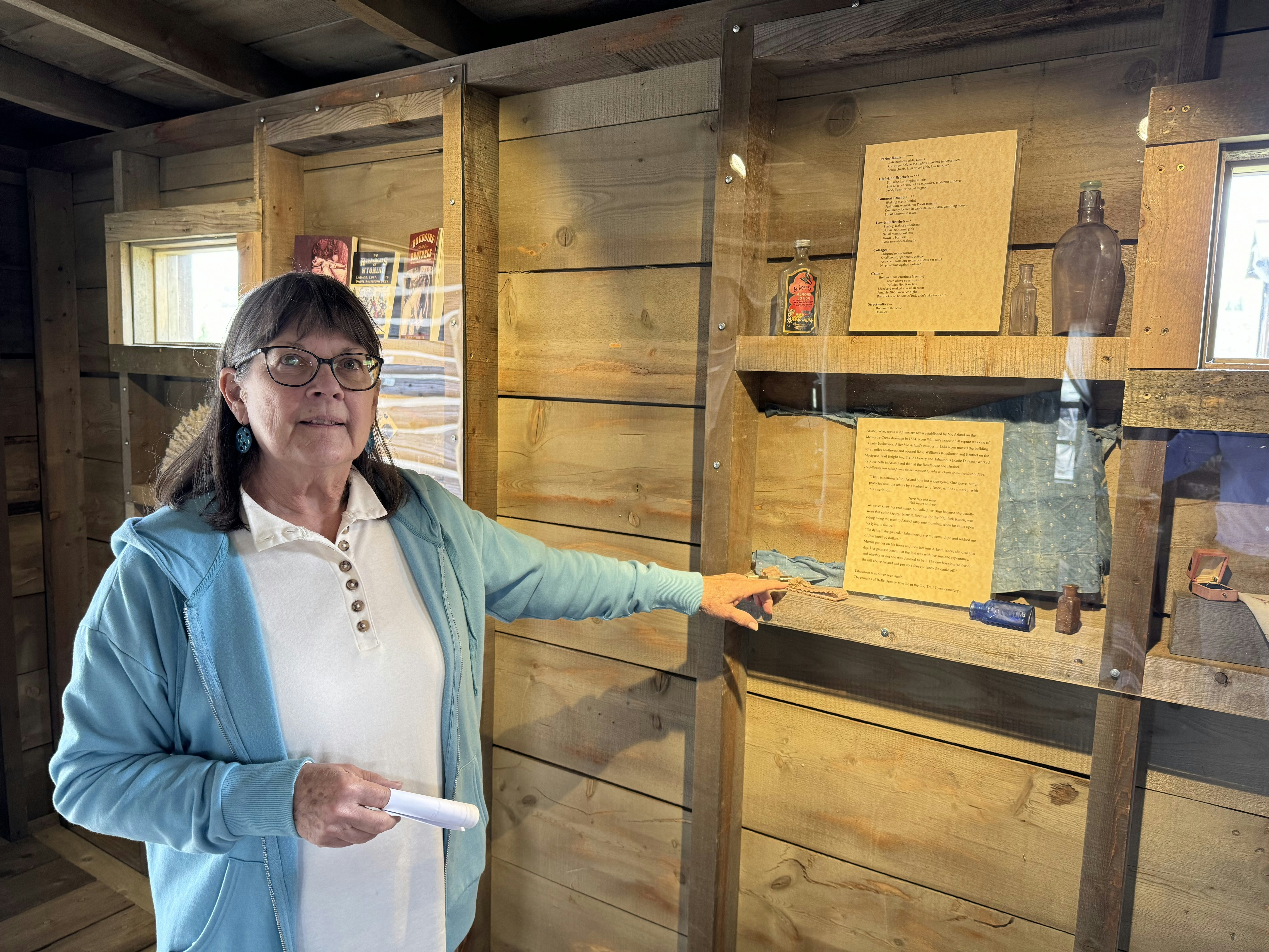 Sylvia Huber, Old Trail Town office and collection manager, points out a display of artifacts and documents telling the sordid story of "the Crib," where Rose Williams' Roadhouse and Brothel carried out its primary business.