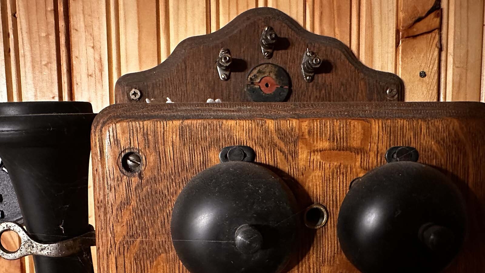 Original wooden phones in Wyoming were connected to wires from the top of the phone and strung outside to fences. Before insulators were installed, there was the danger of lightning strikes running through the wires and coming out of the mouthpieces.