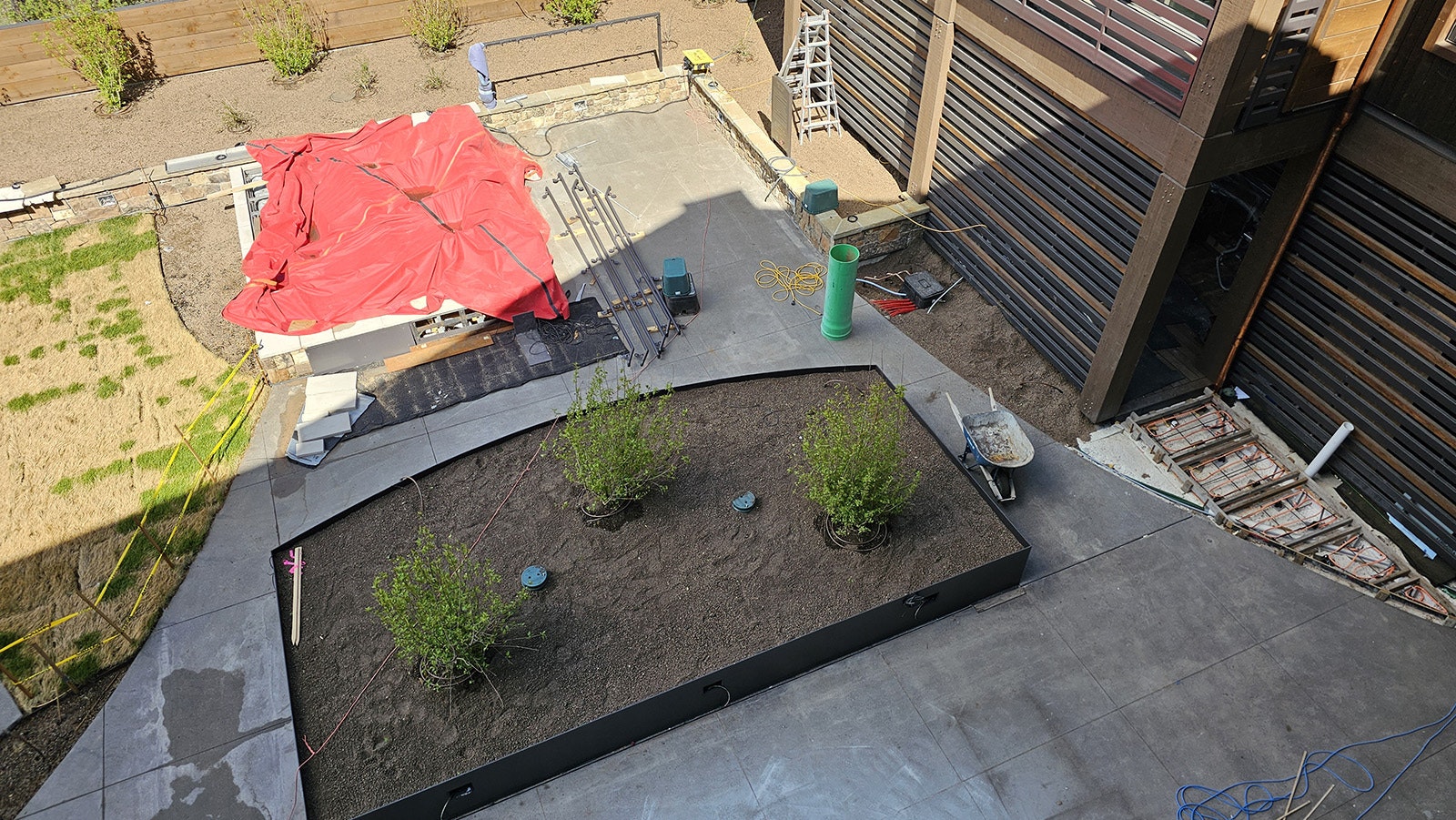 A hottub, covered with the red tarp, in the back of the courtyard will be screened by trees planted in front.