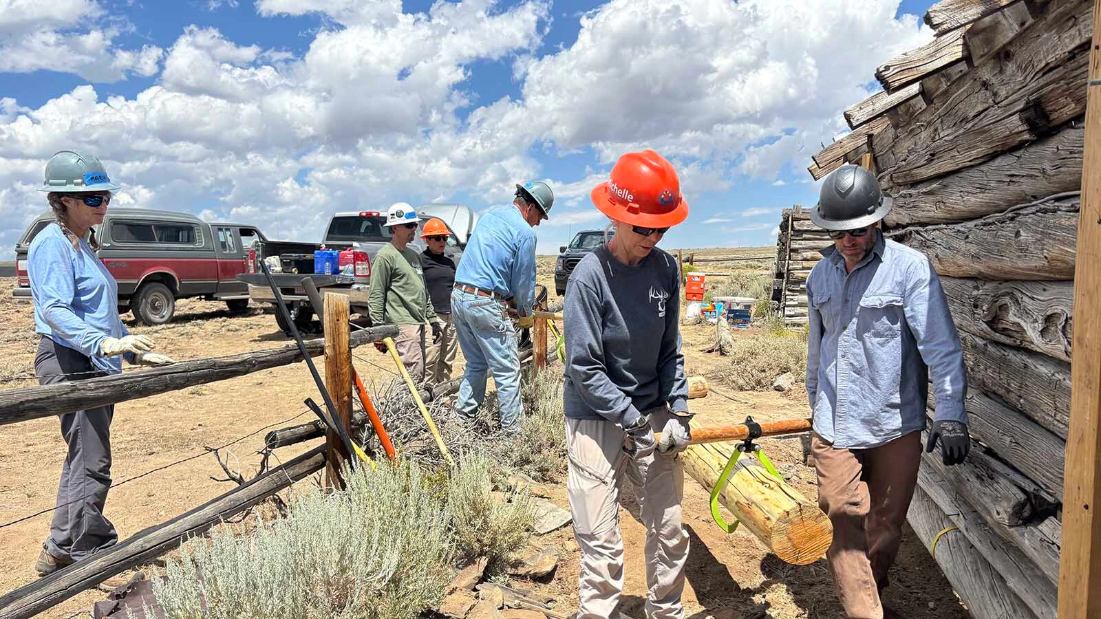 HistoriCorps staff and volunteers carry a replacement sill log at Gillespie Place.