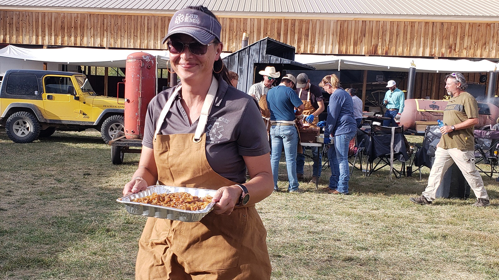 A volunteer carries a tray of prepared smoked meat to the potluck lineup.