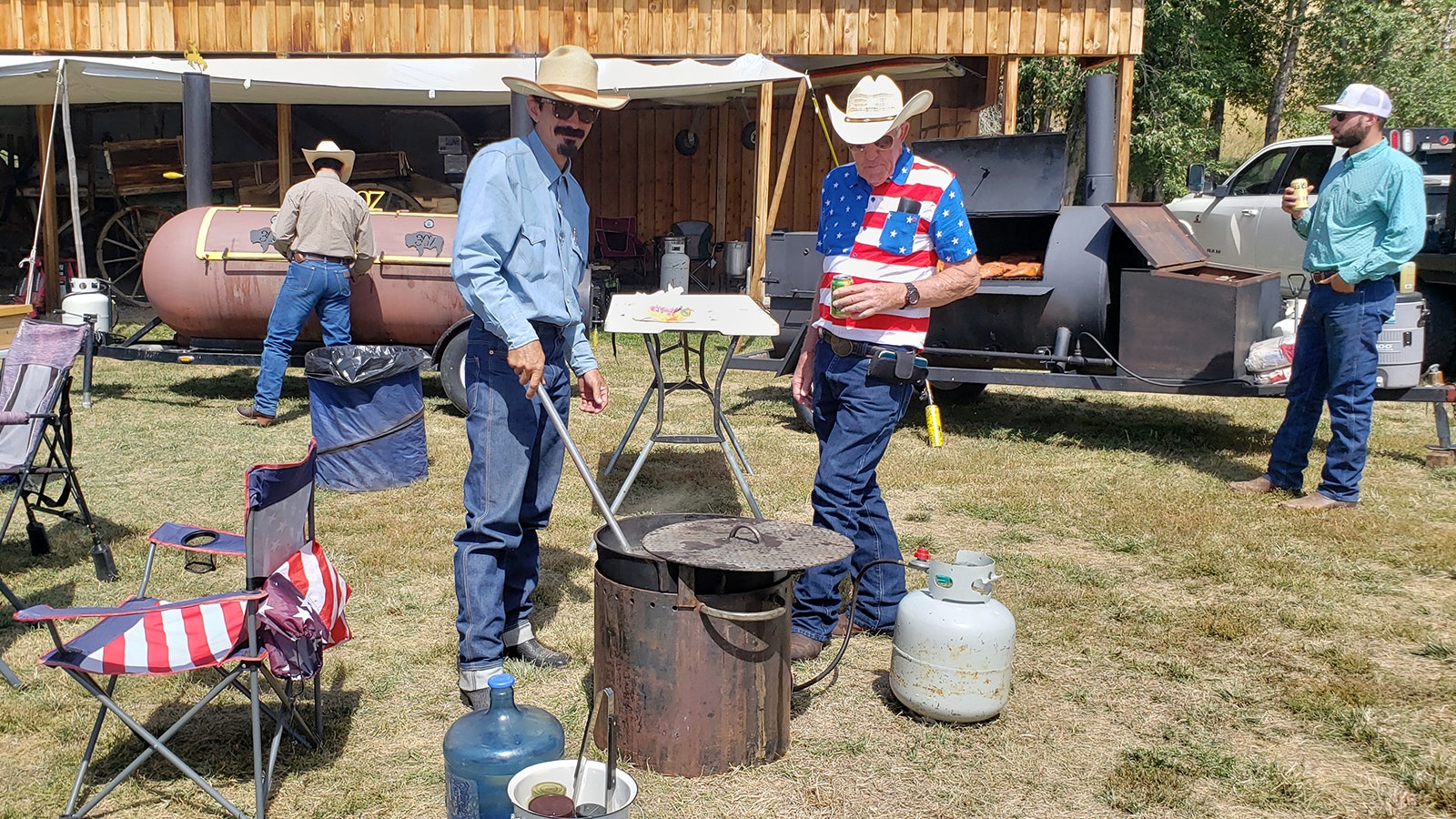 Keith Duncan, left, stirs the pot of community beans he's making for the Savery Picnic while Blaine Woods looks on.