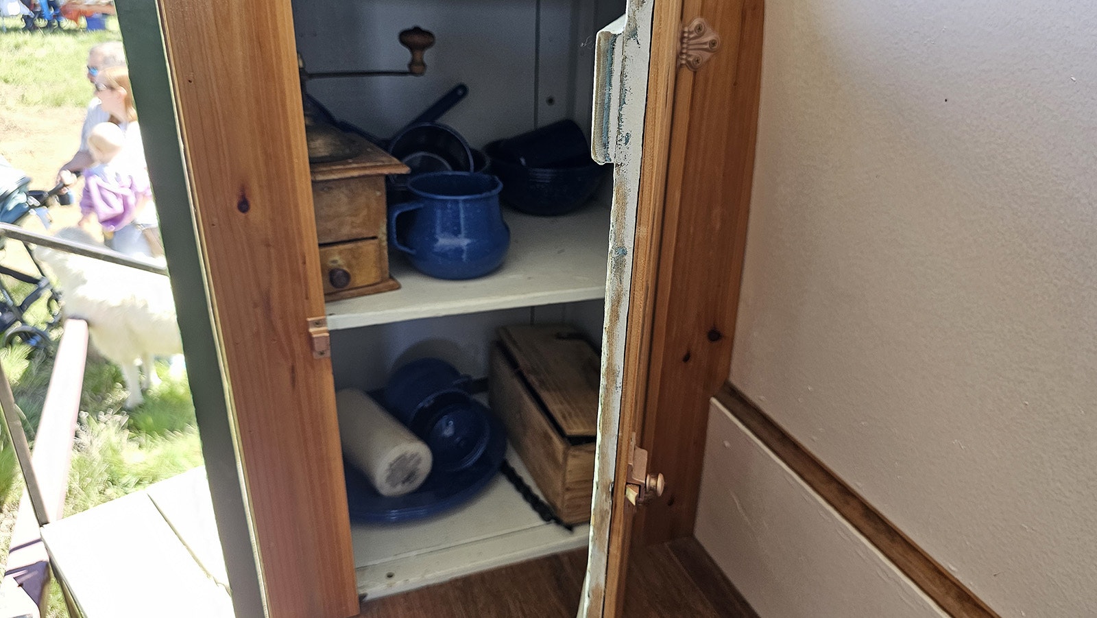 Inside the cupboard on The Pearl, some coffee cups, a coffee grinder, and other dishes.
