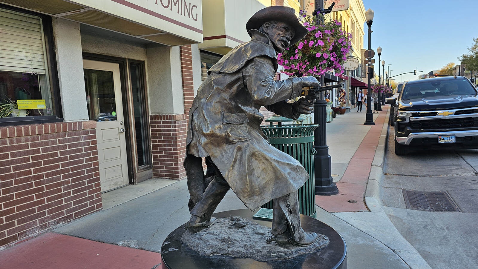 Perpetually shooting at invisible gunmen on Main Street in Sheridan, this statue is a popular one for tourist selfies, right across from the Rainbow Bar and Le Reve, neither of which are pictured.