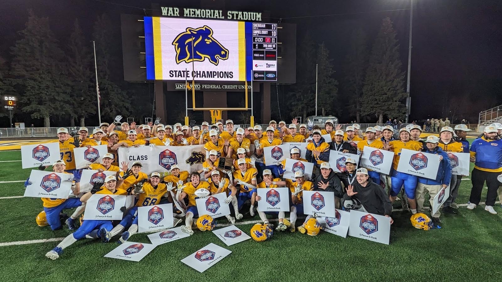 This year’s undefeated football championship run by the Sheridan Broncs was business as usual since former Head Coach Don Julian started a winning tradition current Head Coach Jeff Mowry continues. The secret to their success? Building leadership skills during retreats in the woods. A program describing the retreats includes photos of trust exercises and the team circled up for prayer.