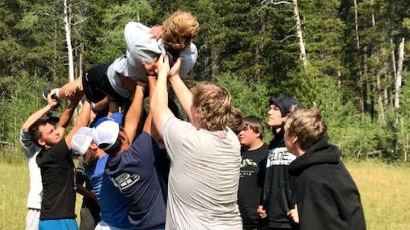 This year’s undefeated football championship run by the Sheridan Broncs was business as usual since former Head Coach Don Julian started a winning tradition current Head Coach Jeff Mowry continues. The secret to their success? Building leadership skills during retreats in the woods. A program describing the retreats includes photos of trust exercises and the team circled up for prayer.