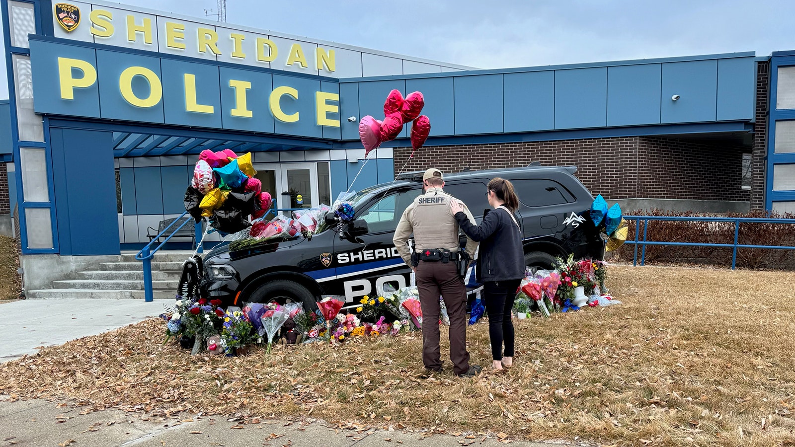 Sheridan County Sheriff's Office Deputy Braydon Dempsey and his wife Addison Dempsey at a memorial for Sheridan Police Sgt. Nevada Krinkee, which has been growing throughout the day Wednesday.