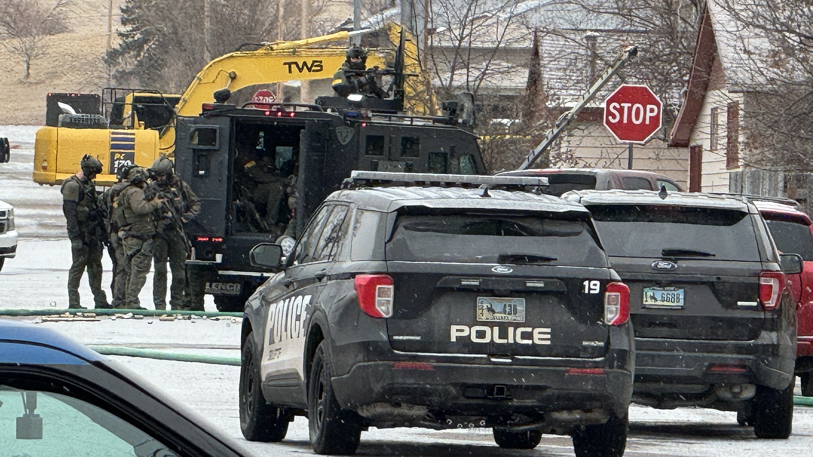 An armored vehicle and police officers in tactical gear outside a home in Sheridan on Feb. 13, 2024, after a man shot and killed a Sheridan police officer.