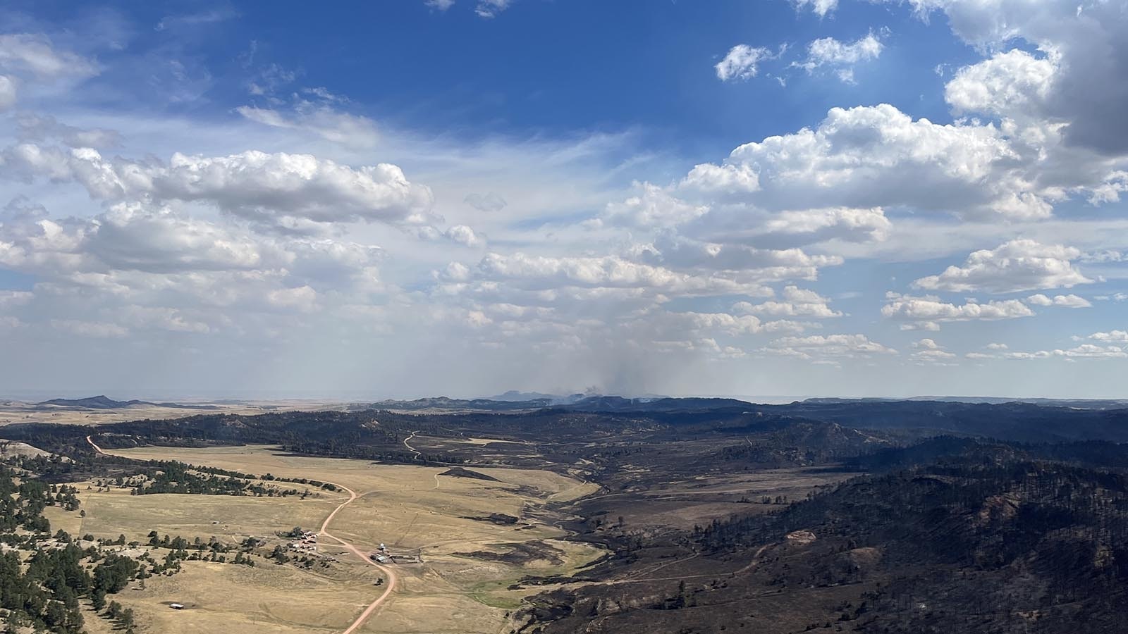 An aerial view of the Short Draw Fire shows acres of black and burned wildland while a homestead that's been saved from the flames.