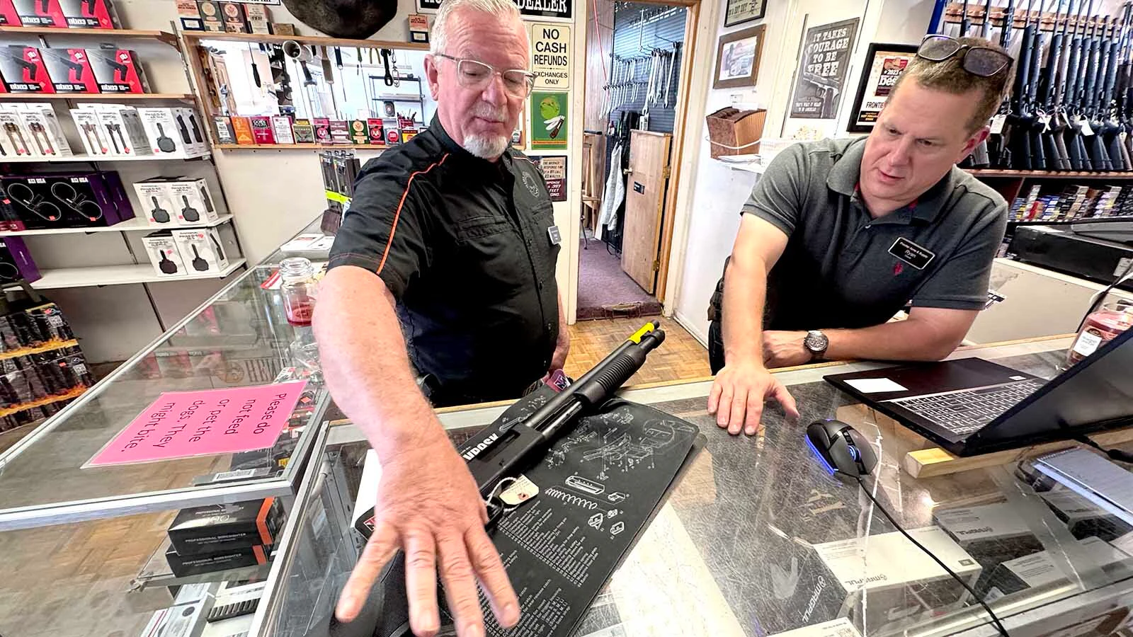 Arthur Huckfeldt, left, demonstrates how the trigger of a shotgun is the only way to make it fire at Frontier Arms and Supply in Cheyenne. Store owner Ryan Allen looks on.