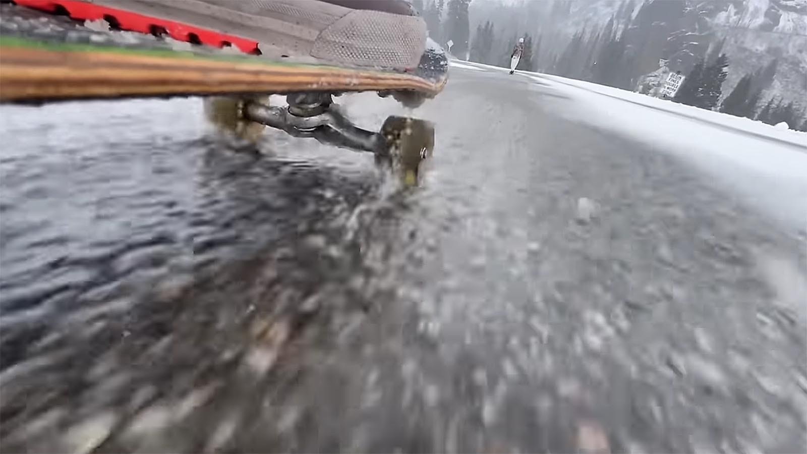 A perspective from the ground skateboarding on a snowy Colorado road.