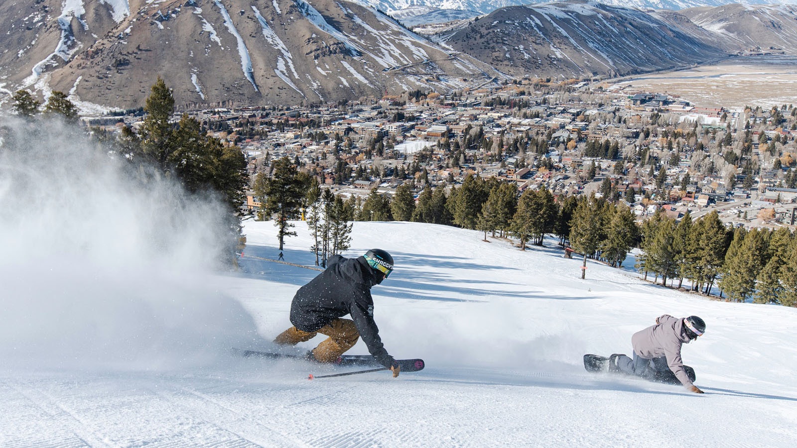 Outdoor recreation around Jackson and Teton County is driving the area to be tops in the nation for its economic boom. Here, a skier and snowboarder carve some snow on Snow King Mountain above Jackson, laid out below.