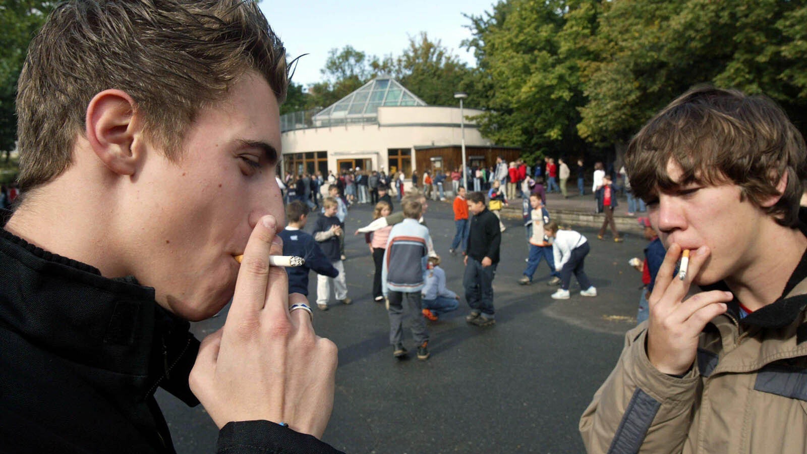 A pair of students smoke outside a public school before class.