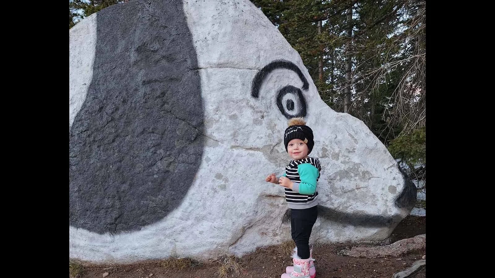 A child poses beneath Snoopy's watchful eye. For some families, stopping at the painted rock has become part of the tradition of heading into the mountains.