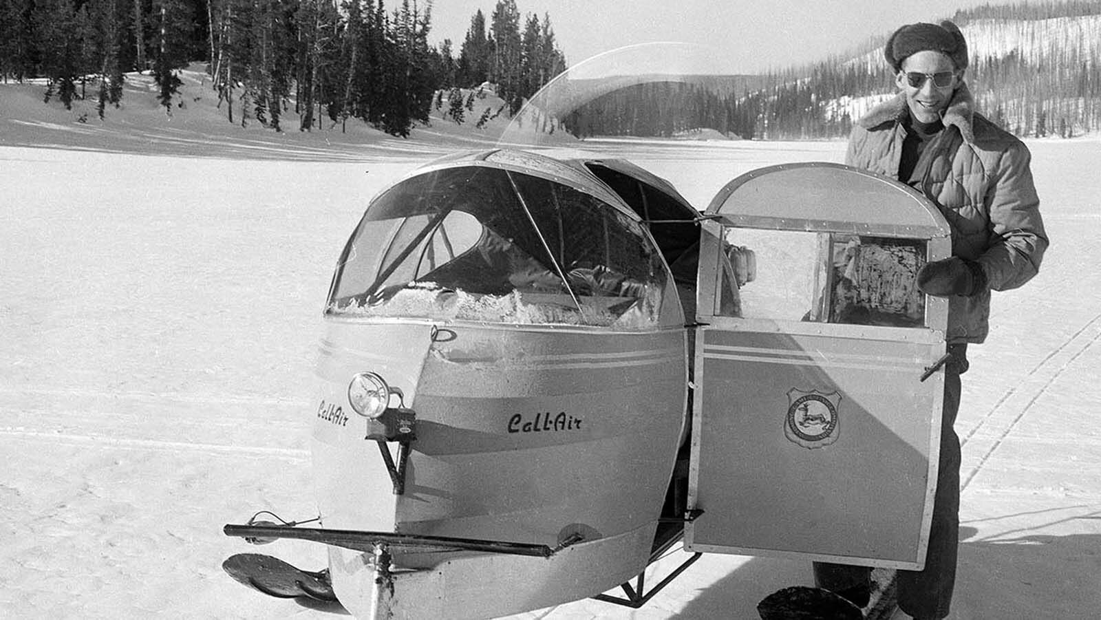 Larry Morrison, editor of the “Cody Enterprise,” standing next to a snow plane on the ice at Lewis Lake, 1955.