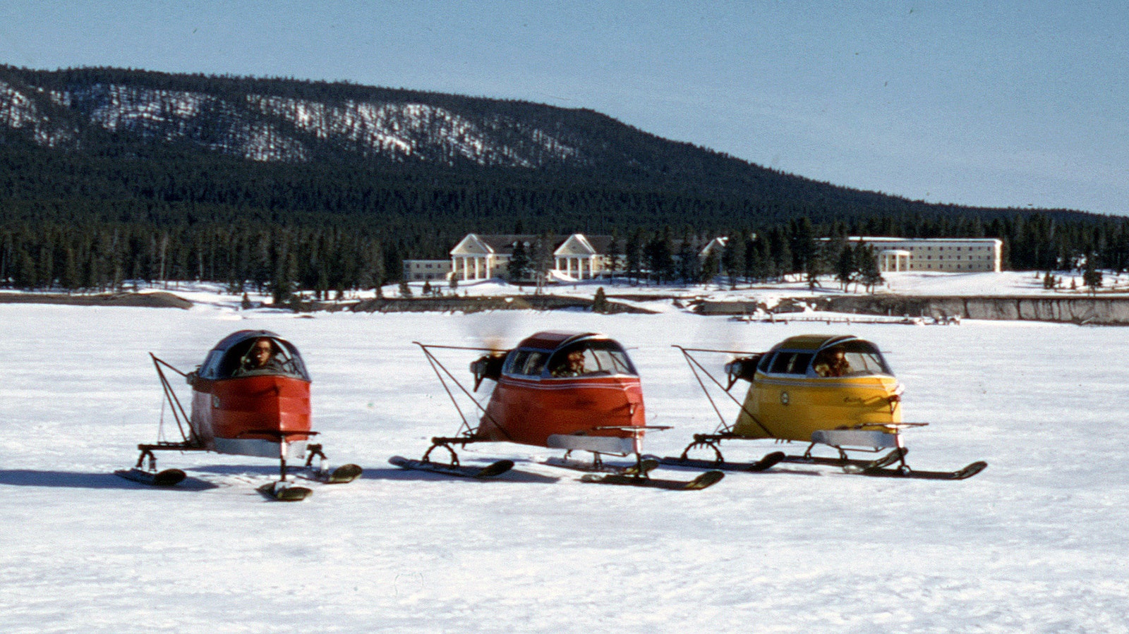 Three CallAir snowplanes moving across Yellowstone Lake in Winter 1955. Once the snowplanes were no longer needed for U.S. Mail deliveries, the National Park Service and Wyoming Game and Fish acquired the vehicles to use in their patrols and scientific expeditions in the snowy interior of Yellowstone.