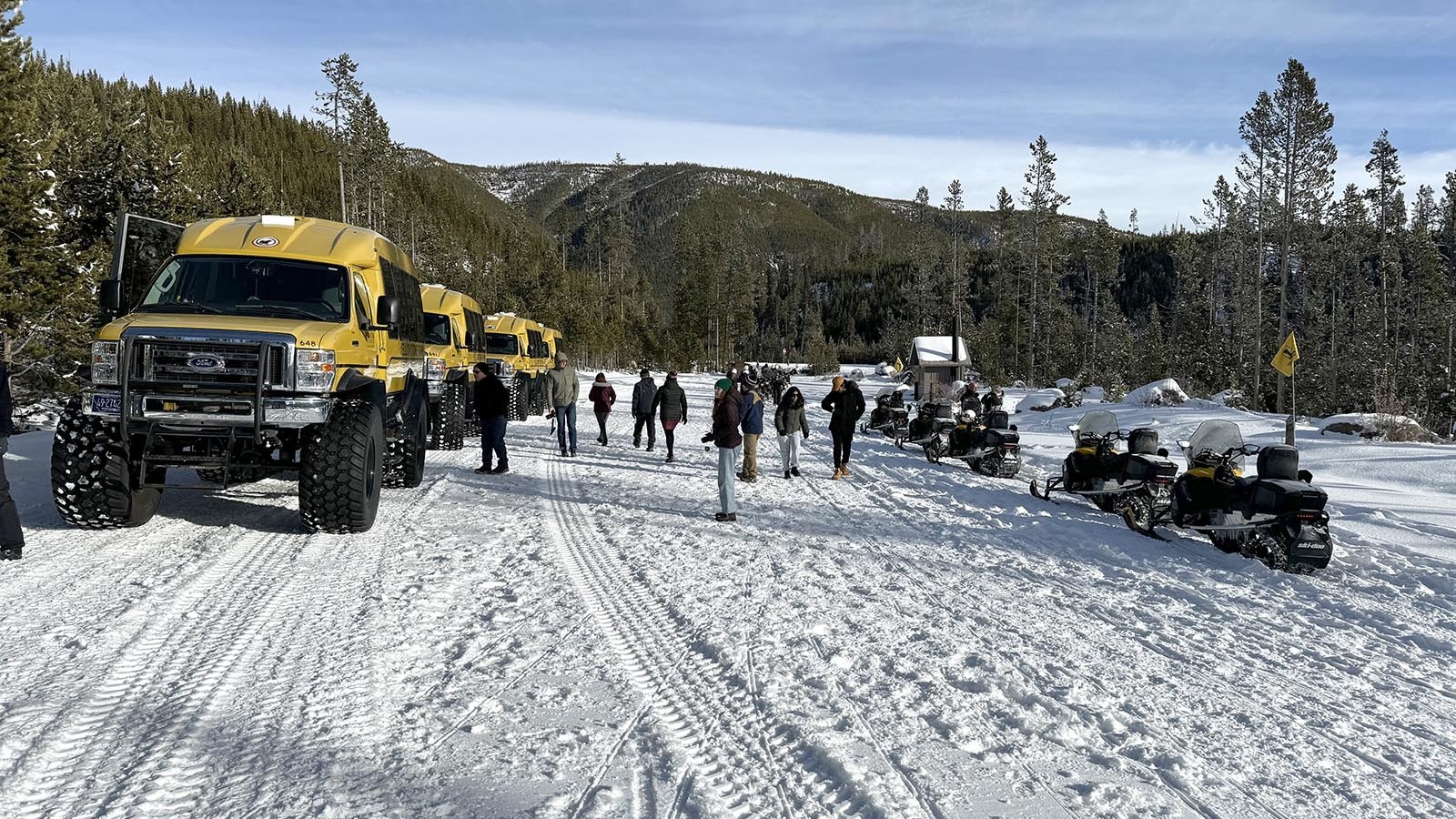 Snow vehicles taking a brief respite at the Gibbon Falls parking lot during a winter tour of Yellowstone National Park.