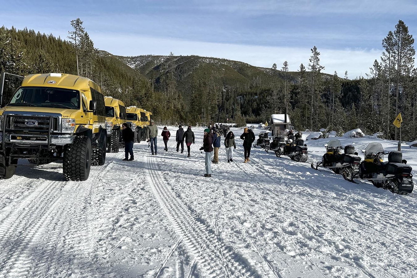 Snow vehicles taking a brief respite at the Gibbon Falls parking lot during a winter tour of Yellowstone National Park.