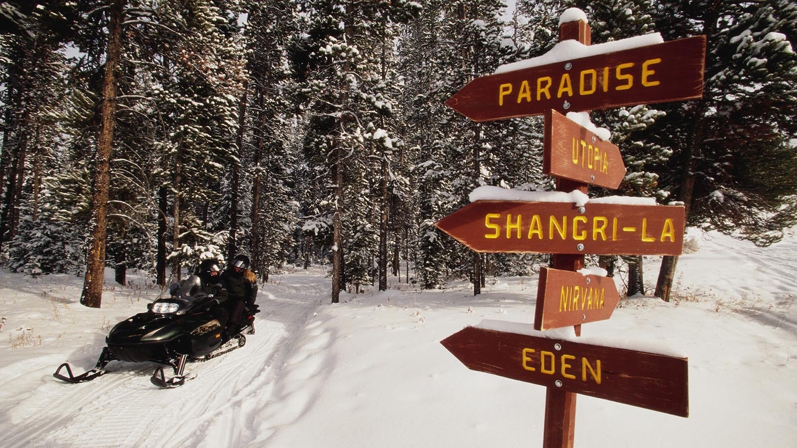 Snowmobilers ride in Towgotee Pass near a sign post in the Bridger-Teton National Forest in Wyoming.