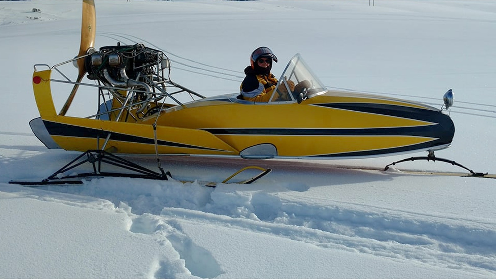 A yellow snowplane created by H.L. Wiese races across the snow.
