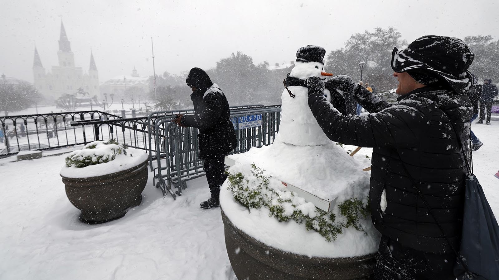 A man builds a snowman in the snow at Washington Artillery Park with the St. Louis Cathedral in the background Jan. 21, 2025, in New Orleans, Louisiana.