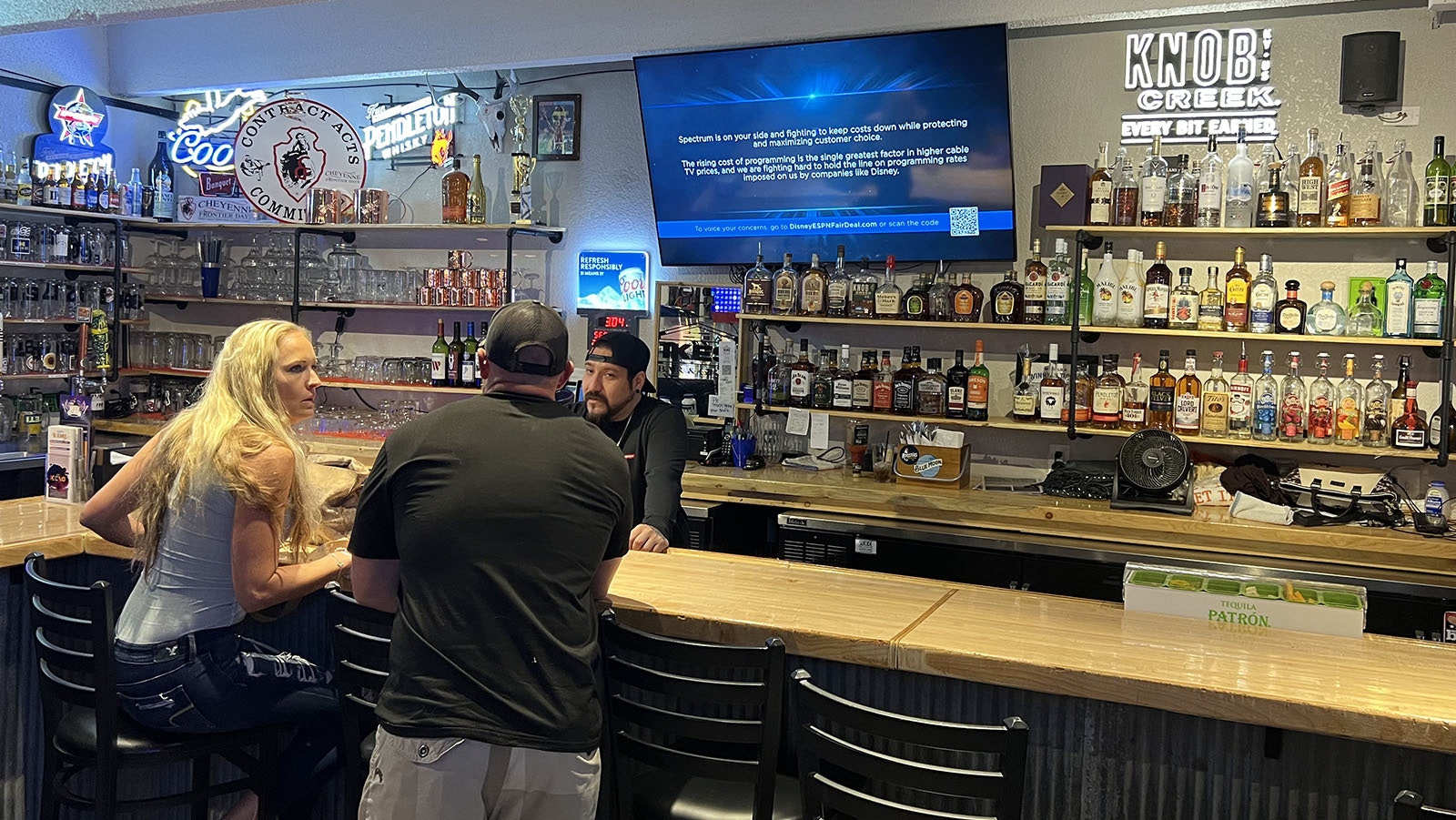 Rob Altamirano serves a pair of customers at Ike's Bar and Grill in south Cheyenne on Thursday, while a message from Charter Spectrum cable plays on ESPN over the back bar. The sports network, and all other Disney channels, have been pulled as a contract dispute between the companies comes to a head.