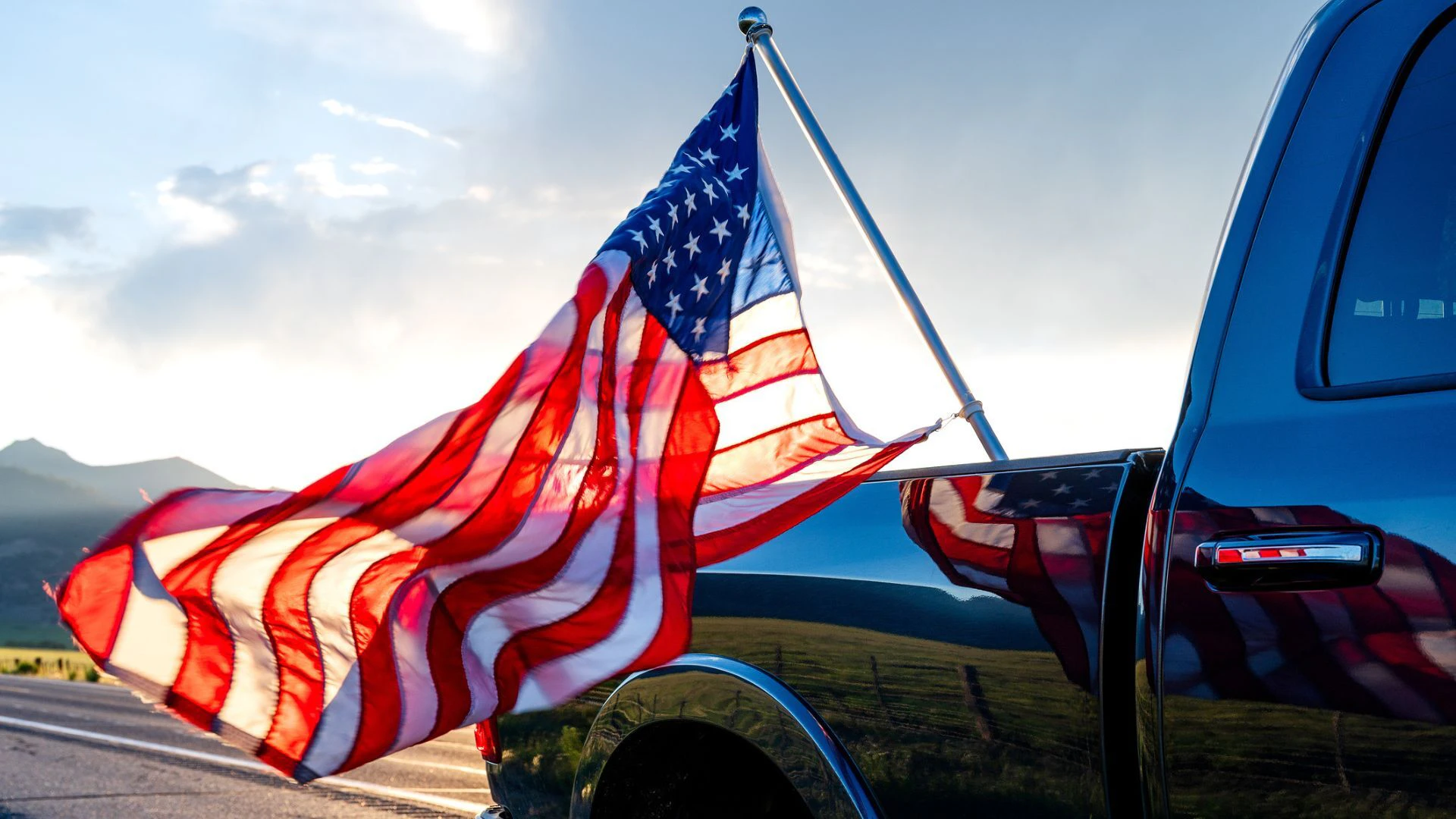 American flag flying out of the back of a pick up.