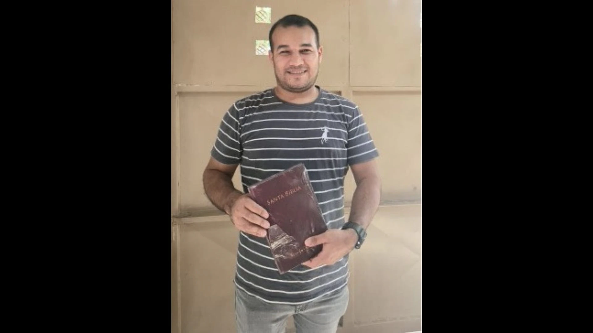 A man holding a Bible and smiling that he has a Bible