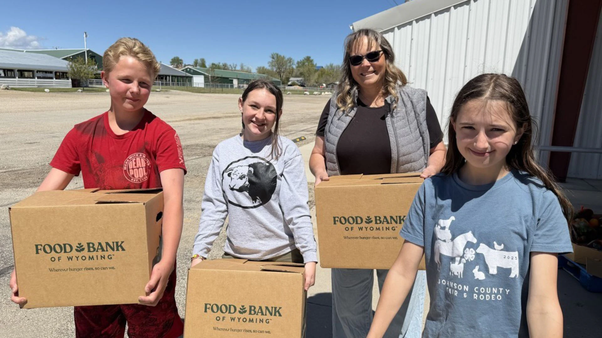 Three teens and one adult volunteering, holding boxes at a Food Bank of Wyoming Mobile Pantry in May 2026.